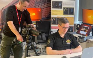 Filming a man working at a laptop in a train-themed office.