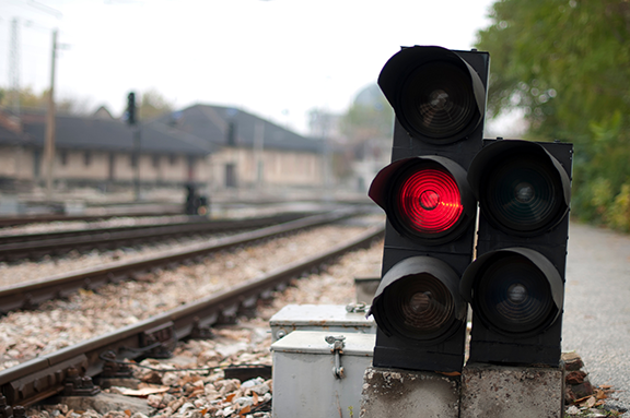 Red railway signal beside train tracks at a station or rail yard